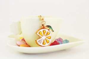 Detail of creative orange slice keychain with sparkling rhinestones and green leaf decor