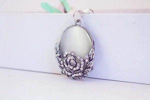 Close-up of cat eye stone pendant with rose flower and sparkling rhinestones