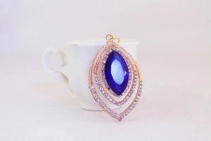 Detailed close-up of rose gold peacock leaf keychain with blue crystal and rhinestones