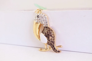 Gros plan du pendentif toucan doré avec cristaux blancs et détails en émail brun