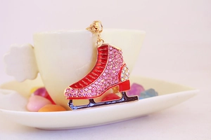 Detail of red rhinestone ice skate keychain hanging on a white ceramic cup