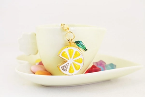 Detailed view of lemon keychain with yellow crystals hanging on a yellow ceramic cup