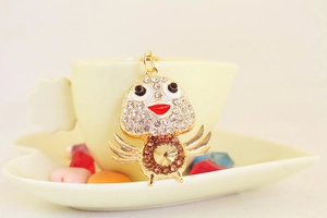 Macro detail of a crystal-encrusted chick keychain with champagne gemstone on a coffee cup