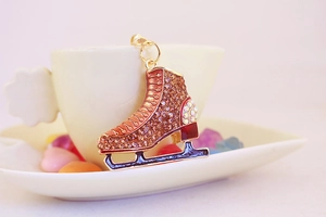 Macro shot of a gold-plated ice skate keychain with rhinestones resting on a ceramic cup