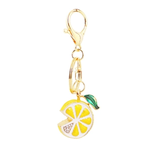 Macro shot of creative lemon fruit keychain with green enamel leaf and white rhinestones