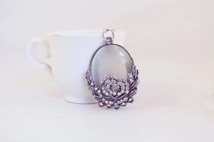 Close-up of vintage oval keychain pendant with grey cat-eye stone and crystal roses