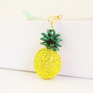 Colorful crystal pineapple keychain with yellow rhinestones and green leaves on white stand
