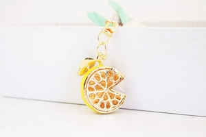 Close-up of a sparkling yellow lemon slice keychain with golden lobster clasp detail
