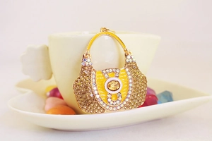 Detailed close-up of a gold crystal handbag keychain resting on a coffee cup