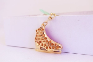 Close-up of golden ice skate keychain featuring hollow floral patterns and lobster clasp