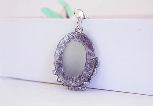 Close-up of vintage silver alloy oval pendant with textured frame and grey opal stone