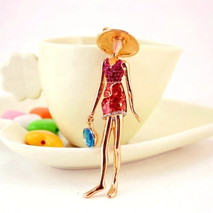 Fashionable lady brooch in gold alloy with red enamel dress and pink crystal accents