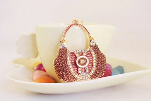 Detailed view of gold rhinestone handbag keychain resting against a cream coffee cup