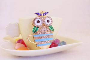 Close-up of colorful owl tea cup keychain with sparkling rhinestones and blue enamel details