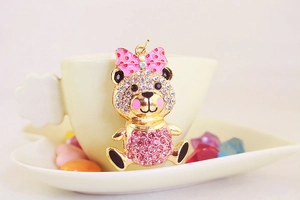 Close-up of sparkling rhinestone bear keychain with a cute pink bow on a porcelain plate