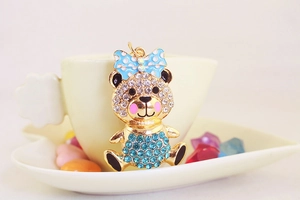Macro view of a golden teddy bear pendant with sparkling blue rhinestones and a bow knot