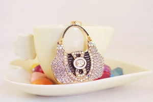 Detailed view of luxury handbag keychain with rhinestones on a ceramic cup