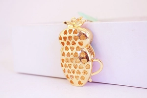 Detailed back view of a golden owl keychain featuring hollow heart-shaped patterns