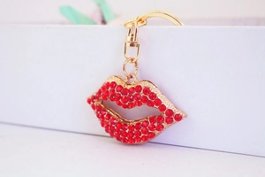Close-up of a stylish red rhinestone lip keychain with a gold metal ring for bags