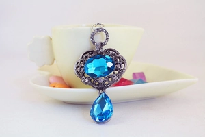 Détail d'un pendentif vintage avec pierre bleue et motifs floraux évidés ciselés