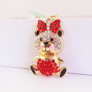 Cute golden bear keychain with red polka dot bow and sparkling rhinestone accents