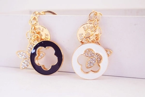 Detail of gold keychain with black and white enamel flower charms and sparkling butterfly crystal