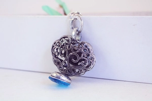 Gros plan d'un pendentif serrure argenté vintage avec cristal bleu et motifs à volutes