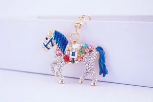 Detail of horse keychain with colorful rhinestones and blue enamel on gold metal