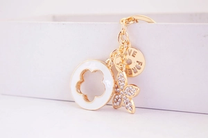 Close-up of gold keychain with crystal flower, enamel ring and Love Forever charm