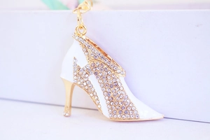 Macro shot of gold-tone high heel keychain with white enamel and sparkling rhinestones