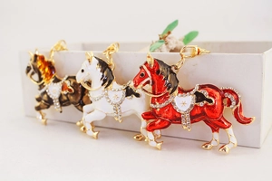 Dettaglio di tre portachiavi a forma di cavallo in metallo con smalto e strass lucidi