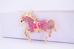 Close-up of golden flying horse keychain with pink rhinestones and enamel details