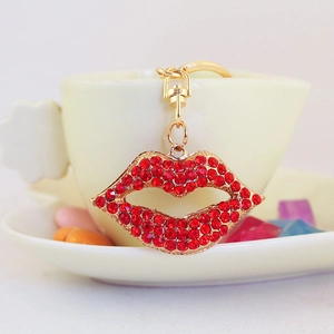Sparkling red rhinestone lip keychain with gold metal frame hanging on a white coffee cup