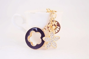 Close-up of golden four-leaf clover keychain with rhinestones and black enamel charm