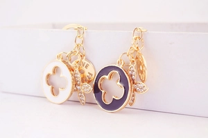 Macro detail of gold metal keychains with floral enamel charms and fine stone inlay