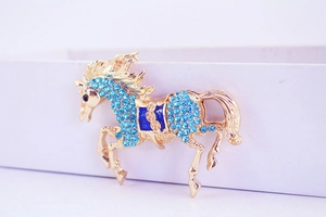Macro shot of gold flying horse keychain with blue rhinestones and enamel saddle detail