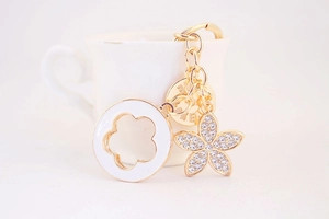 Detailed close-up of golden clover keychain with white enamel petals and sparkling rhinestones