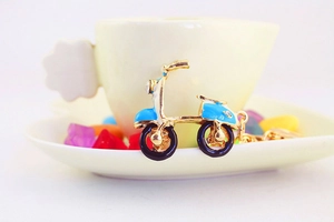 Détail d'un porte-clés moto bleu avec strass posé sur une tasse à café avec décorations