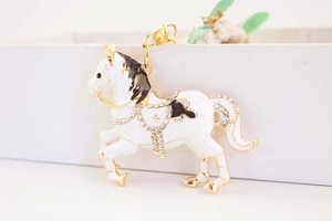 Dettaglio portachiavi a cavallo in smalto bianco con placcatura oro e strass lucidi