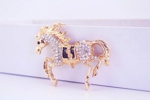 Close-up of golden flying horse keychain with white rhinestones and black enamel detail