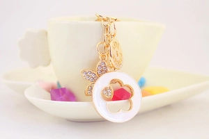 Detail of clover keychain with rhinestones and Love Forever tag on white cup