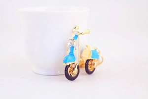 Détail d'un pendentif scooter bleu ciel vintage avec phare en cristal et cadre doré