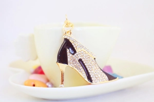 Close-up of rhinestone high heel keychain with black enamel on a coffee cup