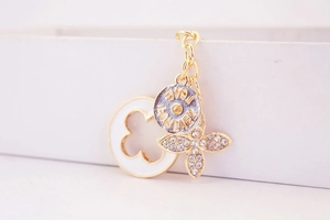 Macro shot of 18K gold clover charm with Love Forever engraving and white enamel