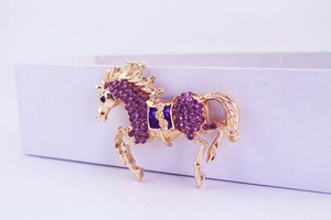 Detailed close-up of golden flying horse keychain with sparkling purple rhinestones