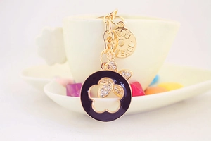 Detailed close-up of a gold clover keychain with purple enamel and LOVE charm on a cup