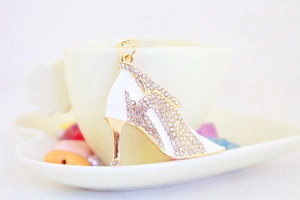Close-up of white enamel high heel keychain with sparkling crystals and gold metal frame