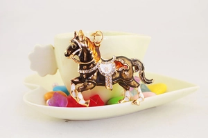 Dettaglio di un portachiavi a forma di cavallo con strass e smalto su una tazza