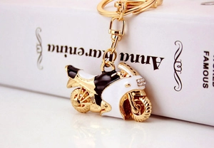 Dettaglio macro di un portachiavi a moto con strass, placcatura in oro e smalto