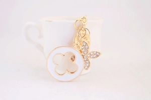 Detailed close-up of gold flower charms with white enamel and sparkling rhinestones